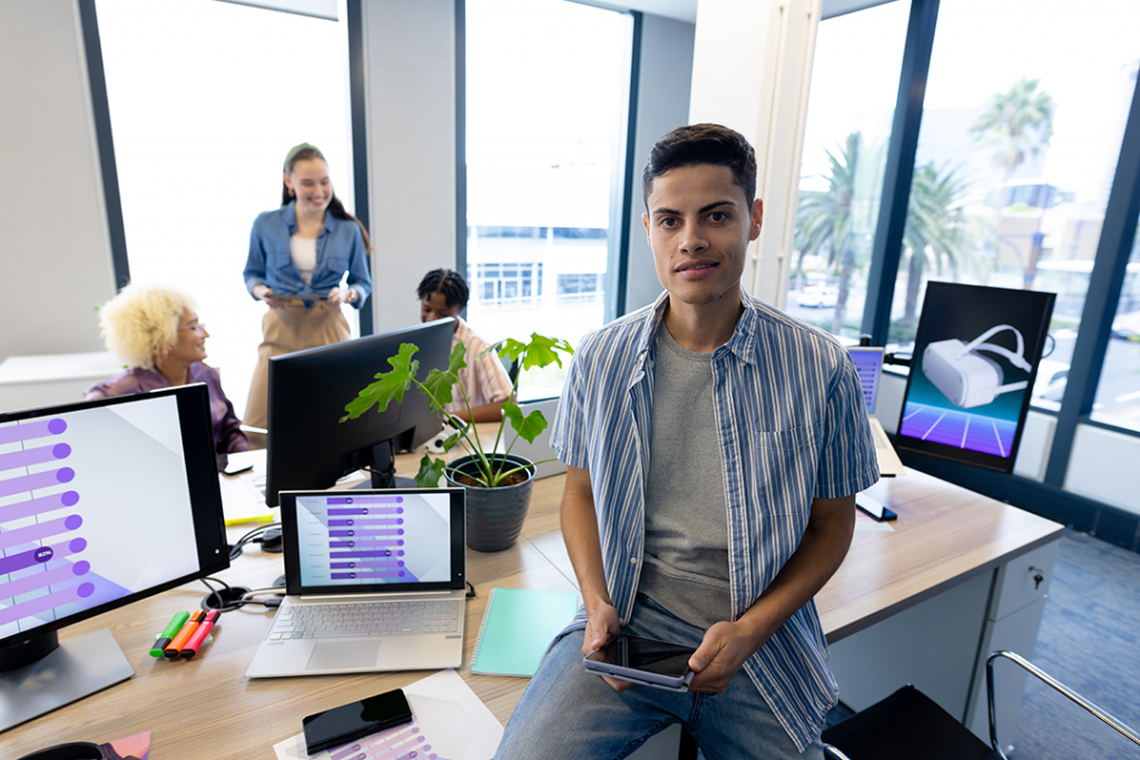 Young tech worker, looking happy and hopeful with his team